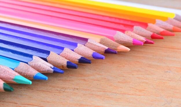Chiuda sulle matite di colore della pila su fondo di legno
