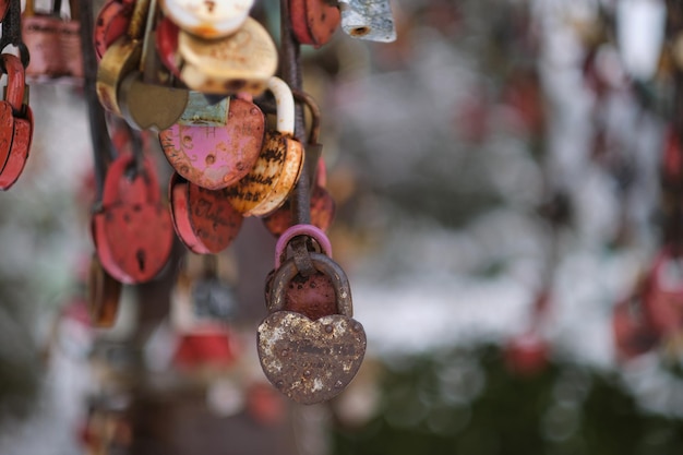 Chiuda sulle vecchie serrature arrugginite a forma di cuore sulla fune metallica amore serratura sul ponte tradizione di appendere a