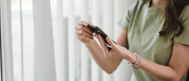 Chiuda sullo smartphone della tenuta della mano della donna, ragazza che utilizza il telefono cellulare a casa.