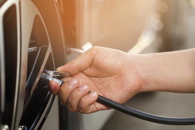 Chiudere fino a mano uomo parcheggio auto un controllo e gonfiare il pneumatico riempire l'aria per una guida sicura in movimento Trasporto viaggio concetto di veicolo