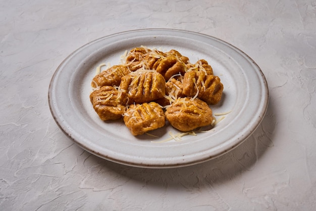 Chiudere gli gnocchi italiani con purea di zucca al forno con farina integrale e parmigiano su piatto leggero acceso