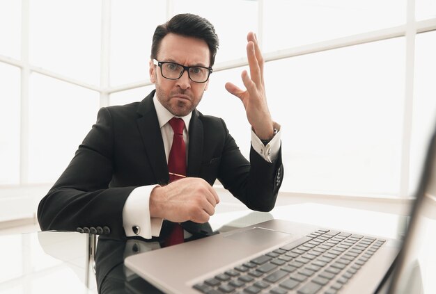 Chiudere i conti correnti di un uomo d'affari serio mentre è seduto al suo concetto di Deskbusiness
