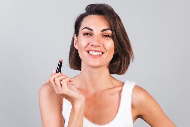 Chiudere il ritratto di bellezza della donna con il trucco e il rossetto marrone sul muro grigio