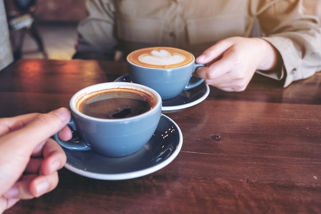 Chiudere l immagine di un uomo e una donna tintinnio tazze da caffè blu sul tavolo di legno nella caffetteria