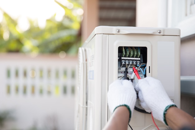 Chiudere la mano del tecnico utilizzando la misurazione per controllare la tensione della corrente elettrica all'interruttore del compressore d'aria esterno.