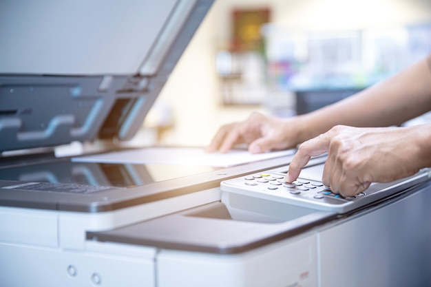 Chiudere la mano dell'uomo dell'ufficio premere il pulsante sulla fotocopiatrice.