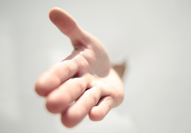 Chiudere la mano di un uomo che sfonda la foto della parete di carta con lo spazio della copia