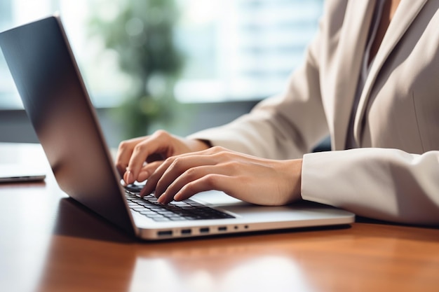 Chiudere la mano di una donna d'affari che digita la tastiera del computer portatile sulla scrivania dell'ufficio