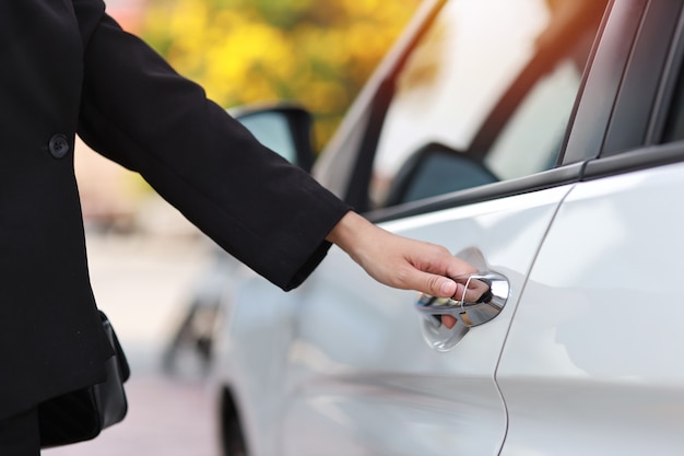 Chiudere la mano femminile di affari che apre la porta dell'auto o dell'automobile