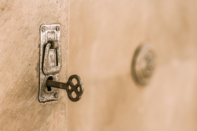 Chiudere la vecchia porta con la vecchia serratura e chiave. Vecchia chiave arrugginita all'interno di un buco della serratura. Messa a fuoco selettiva sulla chiave