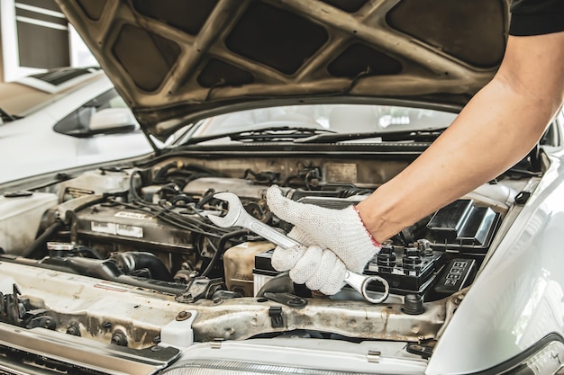 Chiudere le mani del meccanico auto stanno usando la chiave per riparare e mantenere il motore dell'auto