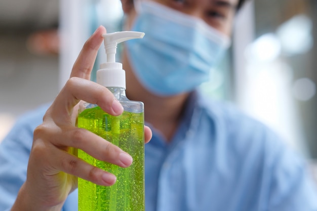 Chiudere le mani dell'uomo utilizzando il lavaggio a mano dispenser di gel disinfettante