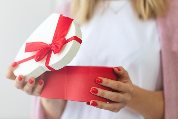 Chiudere le mani della donna tenere il cuore rosso scatola regalo per il giorno di San Valentino consegna presente