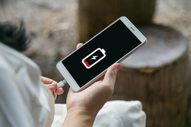 Chiudere le mani di una donna che carica il suo telefono cellulare con l'icona di ricarica
