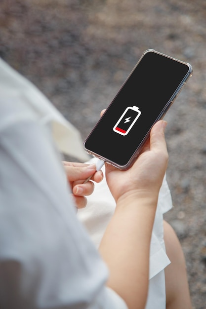 Chiudere le mani di una donna che carica il suo telefono cellulare con l'icona di ricarica