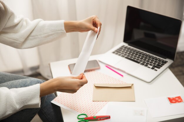 Chiudere le mani femminili facendo biglietti di auguri per Capodanno e Natale 2021 per amici o familiari, prenotazione rottami, fai da te. Scrivere una lettera con i migliori auguri, progettare la sua carta fatta in casa. Vacanze, celebrazione