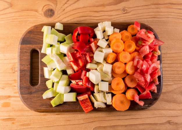 Chiudere le verdure a fette in un tagliere di legno fette di carote pomodori e zucca