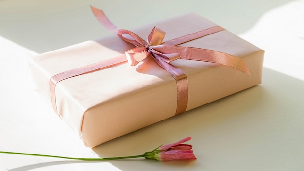 Chiudere un piccolo regalo avvolto con un nastro rosa Confezione regalo su un tavolo con luce naturale
