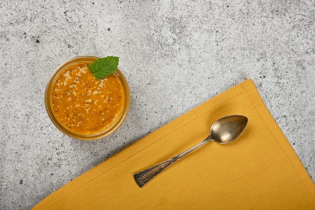 Chiudere un vasetto di vetro trasparente di semi di chia budino dessert con frutti di mango sul tavolo, vista dall'alto in elevazione, direttamente sopra