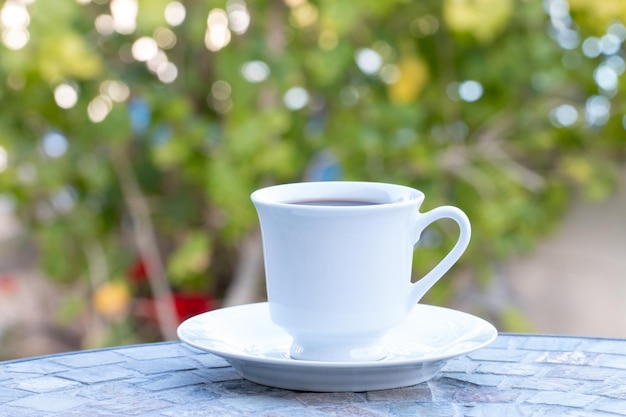 Chiudere una tazza di caffè bianco e un piattino sul tavolo nel cortile