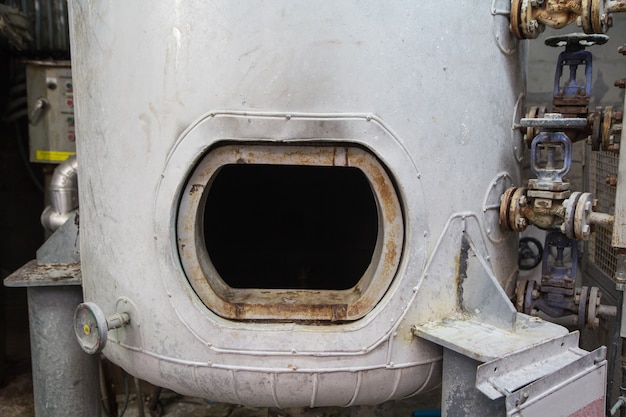 Chiusino arrugginito aperto sullo spazio limitato della nave del serbatoio del carburante bianco