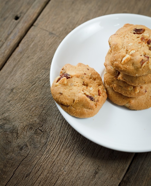 Chocolate chip cookies su disco bianco sul tavolo di legno