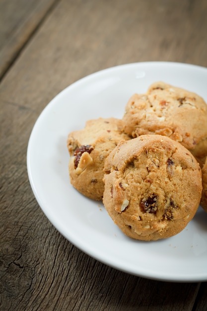 Chocolate chip cookies su disco bianco sul tavolo di legno