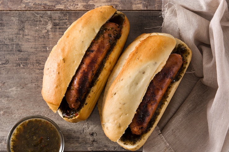 Foto choripan. panino tradizionale dell'argentina con salsa chorizo e chimichurri sulla tavola di legno