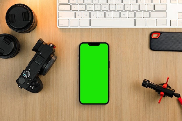 Chroma Key sullo schermo dello smartphone sul tavolo di legno. Ambiente creatore di contenuti con tastiera, fotocamera e microfono. Schermo verde.