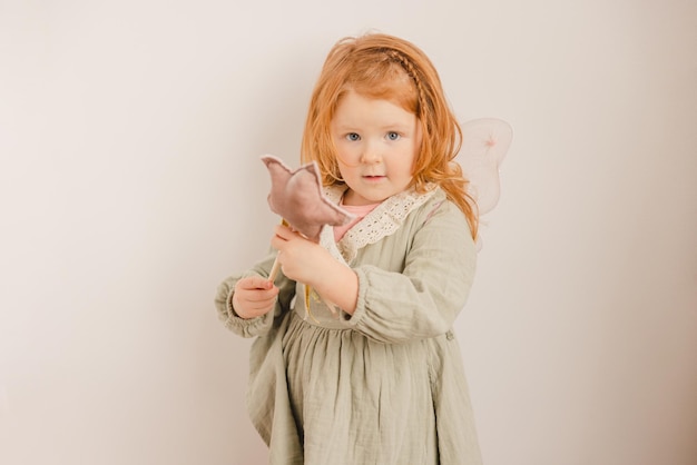 Chubby cute little caucasica bambina con i capelli rossi in abito guarda la fotocamera su sfondo bianco Concetto di stile di vita del bambino