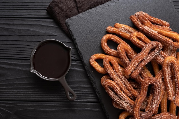 Churros fatti in casa con cioccolato su fondo rustico di legno scuro