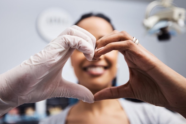 Ci piace vederti sorridere proprio come te Inquadratura ritagliata di un dentista e un paziente che fanno un gesto a forma di cuore con le mani