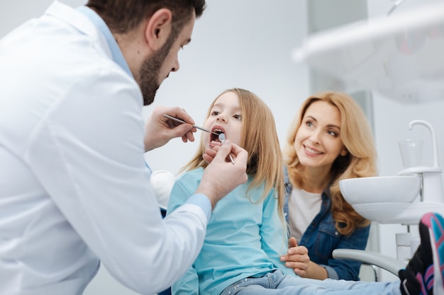 Ci prendiamo cura o denti insieme. Premurosa e amorevole grande madre che si assicura che i denti del suo bambino siano sani pagando visite regolari dal medico