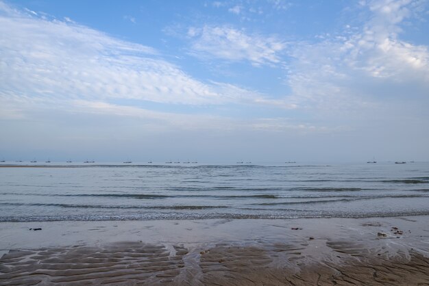 Ci sono cielo azzurro e nuvole bianche sulla spiaggia in riva al mare