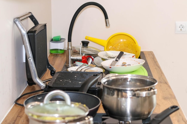 Ci sono molti piatti sporchi nel lavello della cucina Piatti sporchi ed elettrodomestici da cucina non lavati
