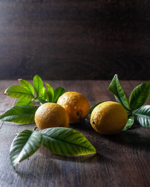 Ci sono tre limoni con erbe sul tavolo.