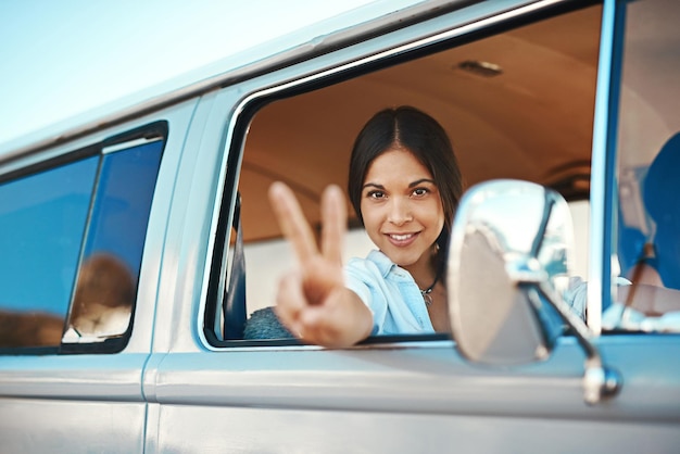 Ci vediamo per strada Inquadratura di una giovane donna che si sporge dal finestrino di un furgone e mostra un segno di pace durante un viaggio