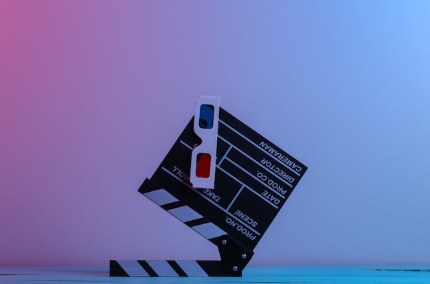 Ciak di film con occhiali 3d in luce al neon blu rossa. Industria dell'intrattenimento