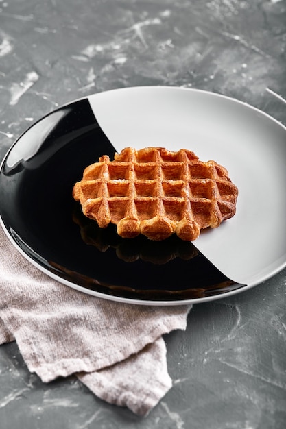 Cialda belga o americana, delizioso piatto dolce, concetto di menu spuntino dessert sul piatto bianco e nero