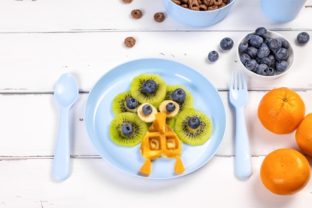 Cialda di pavone per la colazione dei bambini su uno sfondo di legno bianco Adorabile cibo artistico per bambini a forma di animali