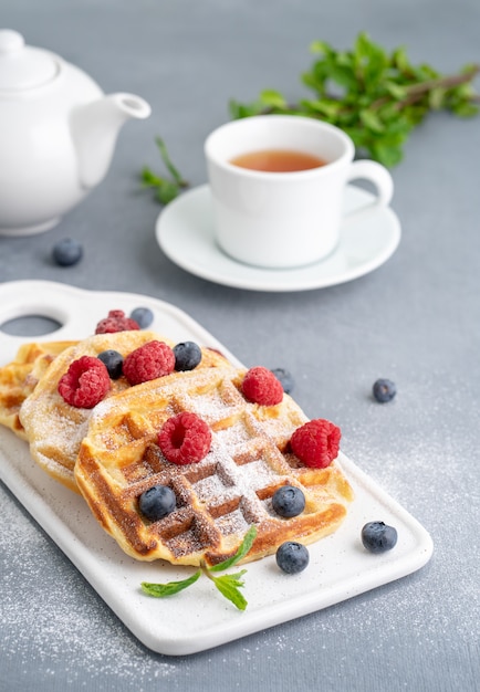 Cialde belghe con lamponi, mirtilli, tè, verticale. Sana colazione fatta in casa