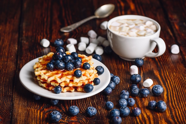 Cialde belghe sulla piastra con mirtilli freschi e tazza di cioccolata calda con marshmallow