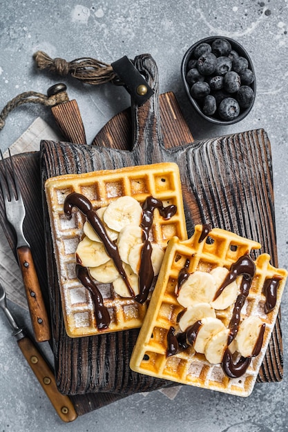 Cialde belghe tradizionali con banana fresca e salsa al cioccolato Sfondo grigio Vista dall'alto