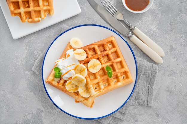 Cialde con panna montata alla banana e caramello salato su fondo grigio cemento