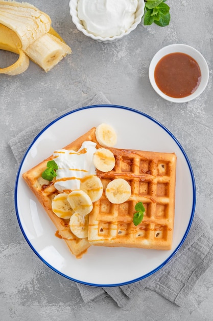 Cialde con panna montata alla banana e caramello salato su fondo grigio cemento