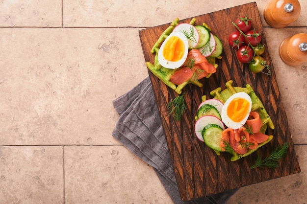 Cialde salate Colazione cialde verdi aglio selvatico o spinaci con uovo pomodoro salmone su piatto di legno per colazione su sfondo vecchio tavolo piastrellato Cena leggera pranzo o colazione Vista dall'alto Mock up