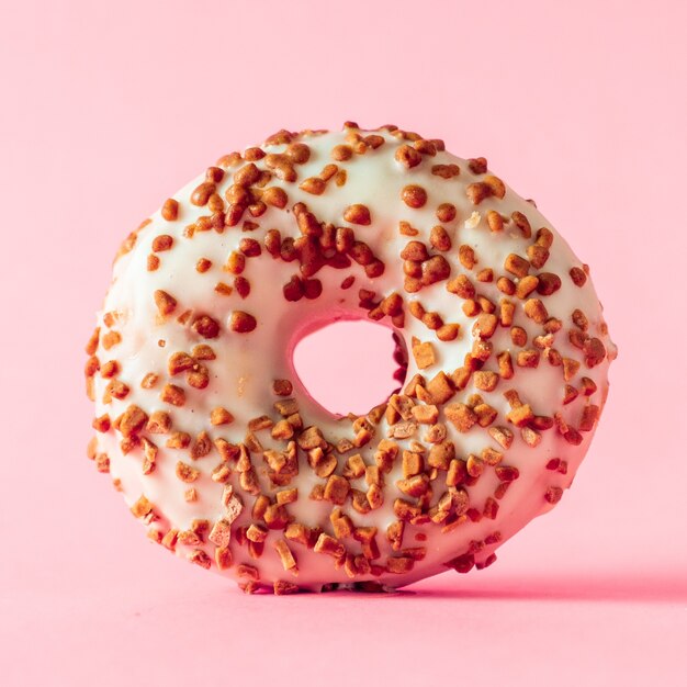 Ciambella al cioccolato bianco con topping di mandorle su sfondo rosa