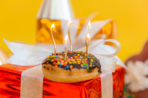 Ciambella al cioccolato dolce e candele accese su uno sfondo bokeh festivo. Buon compleanno concetto.