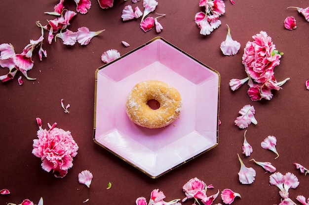 Ciambella alla crema su piatti con petali di dianthus su superficie marrone