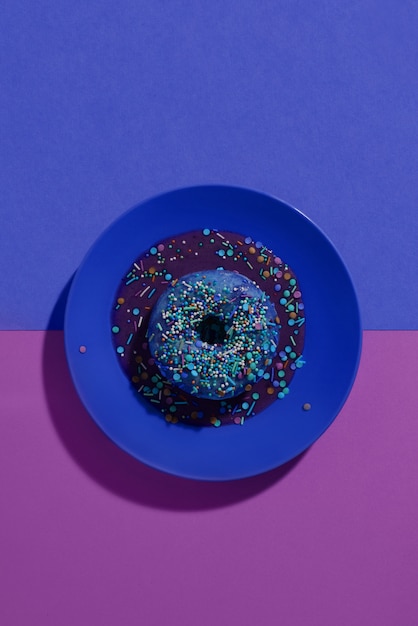 Ciambella blu con vetri viola e polvere multicolore su un piatto blu.